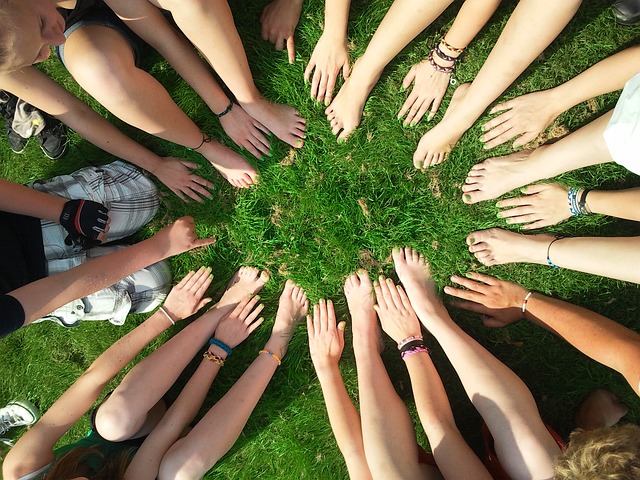 Groupe de jeunes formant un cercle avec leurs bras et leurs jambes dans l'herbe.