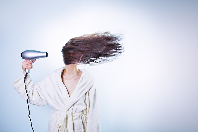 Une femme qui se sèche les cheveux avec les cheveux dans les yeux.